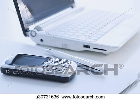 Stock Photograph - Cell phone and laptop on desk. Fotosearch