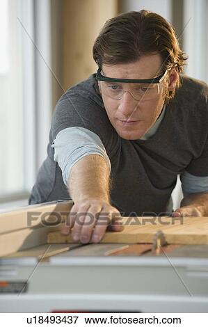 Stock Photo - Construction worker cutting board. Fotosearch