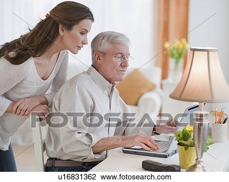 Stock Image - Daughter helping senior father with computer. Fotosearch