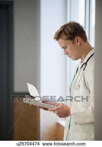 Picture - Doctor reading medical chart. Fotosearch