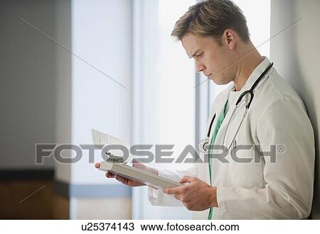 Stock Image - Doctor reading medical chart. Fotosearch