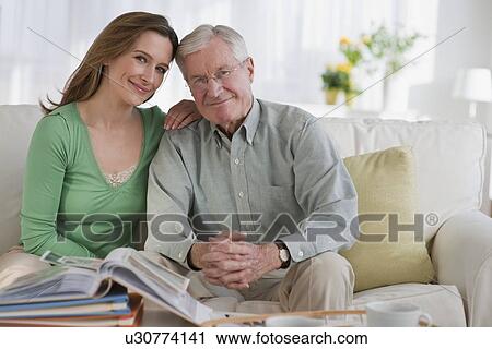 Stock Image - Father an daughter looking at photo albums. Fotosearch