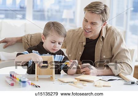Stock Photo - Father and son building wooden model. Fotosearch