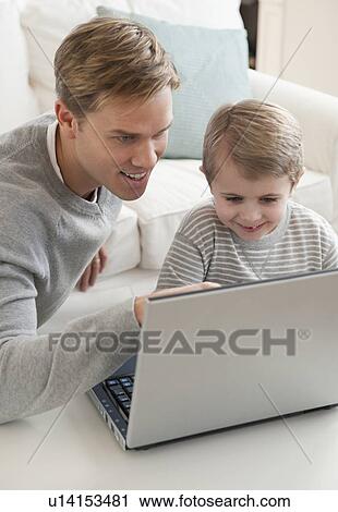 Stock Image - Father and son looking at laptop. Fotosearch