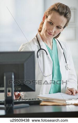 Female doctor looking at computer monitor View Large Photo Image Stock Photo - Female doctor looking at computer monitor. Fotosearch