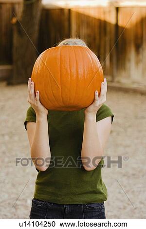 Girl holding pumpkin over face View Large Photo Image Stock Image - Girl holding pumpkin over face. Fotosearch
