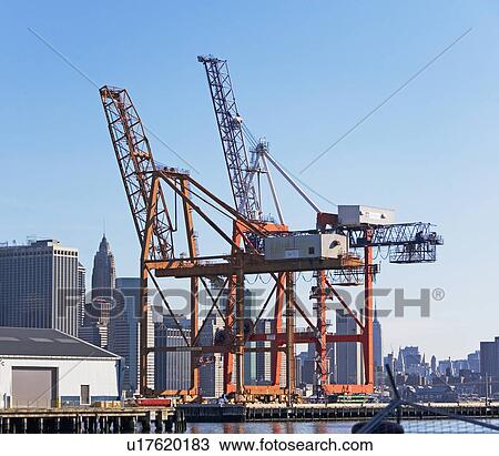 Stock Image - Loading dock cranes and cityscape. Fotosearch