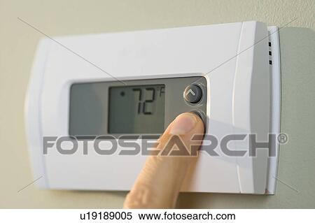 Stock Photography - Man adjusting thermostat. Fotosearch