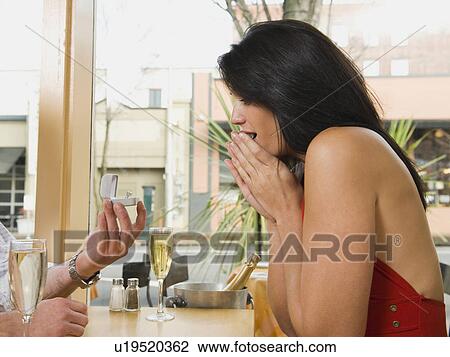 Man giving girlfriend engagement ring in restaurant View Large Photo Image Stock Image - Man giving girlfriend engagement ring in restaurant. Fotosearch