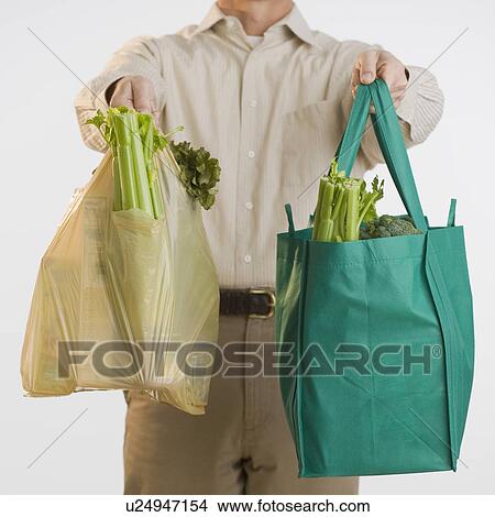 Picture - Man holding reusable grocery bags. Fotosearch