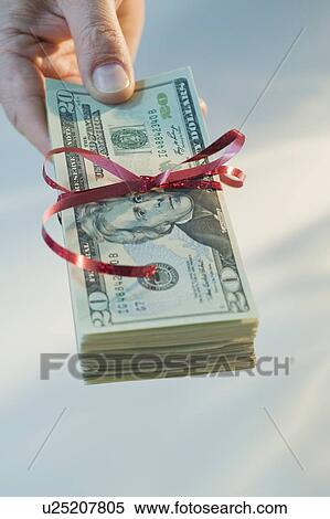 Stock Photography - Man holding stack of money wrapped in ribbon. Fotosearch