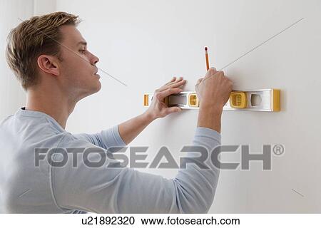 Stock Image - Man marking on wall with level. Fotosearch