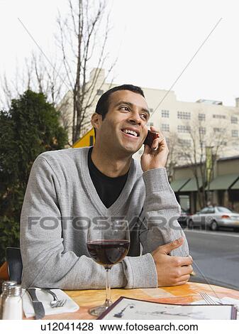 Man talking on cell phone at outdoor cafe View Large Photo Image Stock Photo - Man talking on cell phone at outdoor cafe. Fotosearch