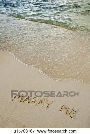 Stock Photo - Marry me message written in sand. Fotosearch