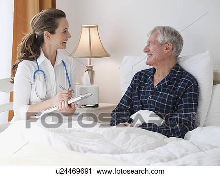 Stock Image - Nurse caring for senior man in bed. Fotosearch