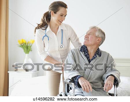 Stock Image - Nurse helping senior man in wheelchair. Fotosearch
