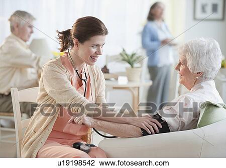 Stock Image - Nurse taking senior woman’s blood pressure. Fotosearch