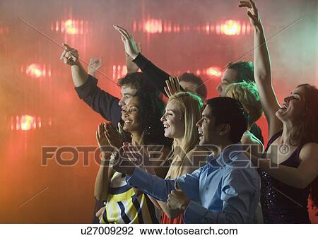 Stock Image - People enjoying concert. Fotosearch