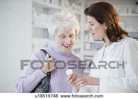 Stock Photo - Pharmacist helping senior woman with prescription. Fotosearch