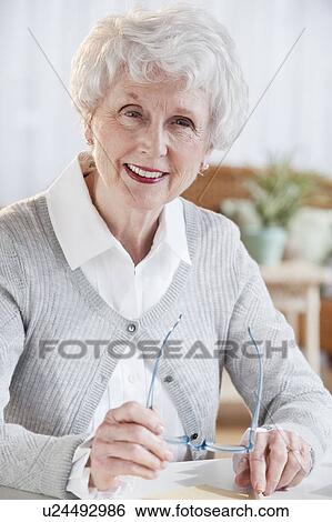 Portrait of senior woman sitting at table View Large Photo Image Stock Photograph - Portrait of senior woman sitting at table. Fotosearch