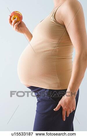 Pregnant woman eating apple View Large Photo Image Stock Photo - Pregnant woman eating apple. Fotosearch