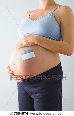 Picture - Pregnant woman with blue name tag on belly. Fotosearch