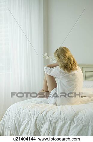 Picture - Sad woman sitting on bed. Fotosearch