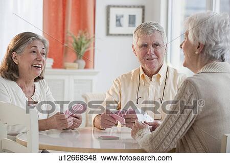 Stock Photo - Senior adults playing cards. Fotosearch