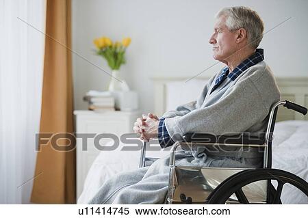 Stock Photography - Senior man in wheelchair looking out window. Fotosearch