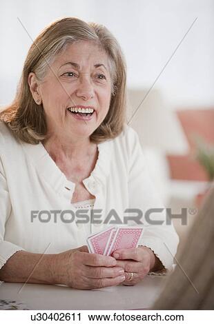 Stock Image - Senior woman playing cards. Fotosearch