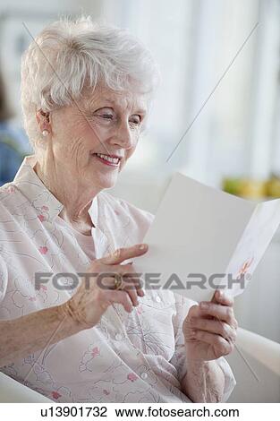 Stock Image - Senior woman reading greeting card. Fotosearch