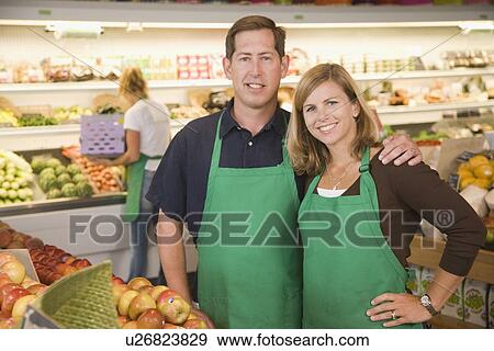Stock Photo - Store owners posing in produce section. Fotosearch
