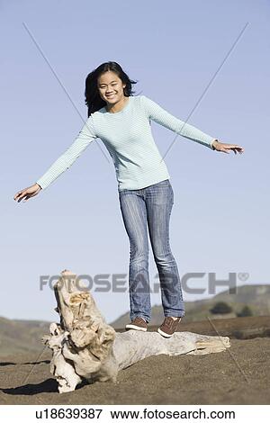 Teenage girl balancing on driftwood View Large Photo Image Stock Photo - Teenage girl balancing on driftwood. Fotosearch