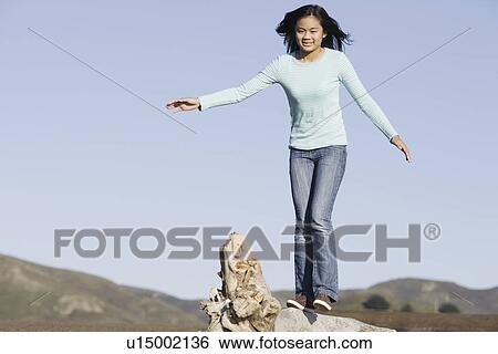 Stock Photograph - Teenage girl balancing on driftwood. Fotosearch