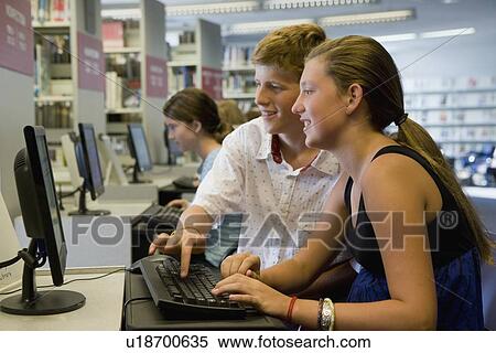 Stock Photography - Teenagers using computer in library. Fotosearch