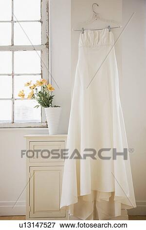 Wedding dress hanging in bed room View Large Photo Image Stock Photo - Wedding dress hanging in bed room. Fotosearch