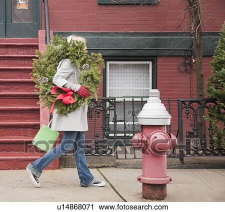 Woman carrying Christmas wreath on urban street View Large Photo Image Stock Image - Woman carrying Christmas wreath on urban street. Fotosearch