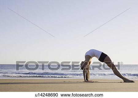 Stock Image - Woman doing yoga on beach. Fotosearch