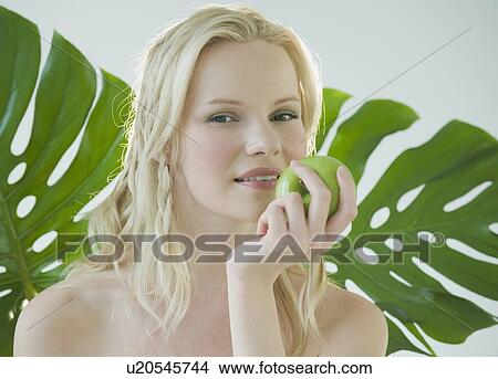 Picture - Woman eating green apple. Fotosearch