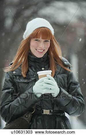 Stock Image - Woman holding coffee in snow. Fotosearch
