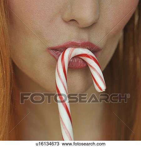 Stock Image - Woman kissing candy cane. Fotosearch