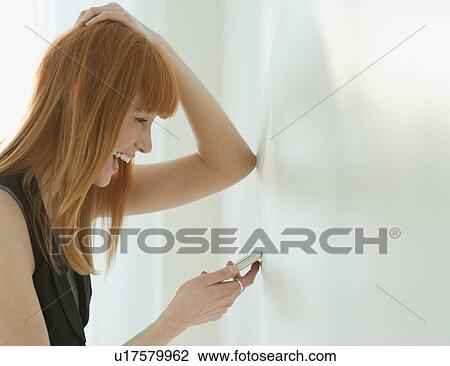 Stock Image - Woman laughing at cell phone. Fotosearch