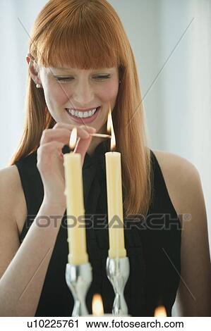 Stock Image - Woman lighting holiday candles. Fotosearch
