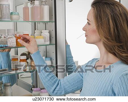 Woman looking in medicine cabinet View Large Photo Image Stock Image - Woman looking in medicine cabinet. Fotosearch