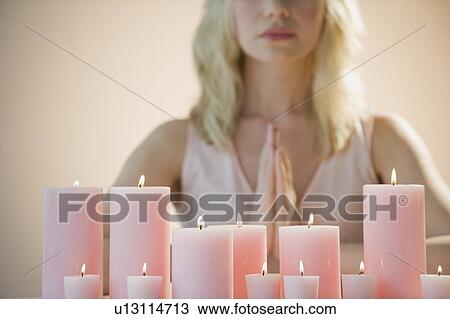 Stock Image - Woman meditating with candles. Fotosearch