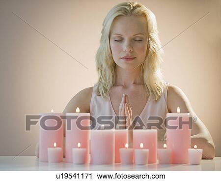 Stock Image - Woman meditating with candles. Fotosearch