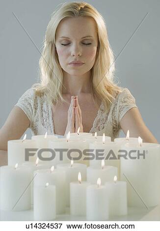 Stock Photo - Woman meditating with candles. Fotosearch