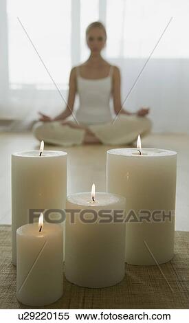 Stock Photography - Woman meditating with candles. Fotosearch