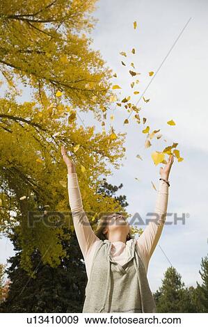 Stock Photo - Woman throwing autumn leaves in air. Fotosearch