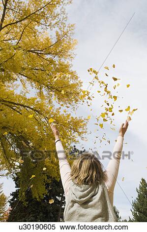 Stock Photography - Woman throwing autumn leaves in air. Fotosearch